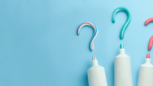Colorful toothpaste swirls shaped like question marks alongside toothpaste tubes on a blue background.