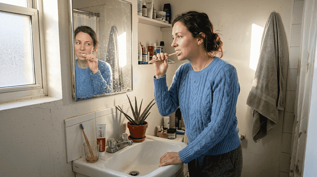 Woman brushing teeth gently in small bathroom