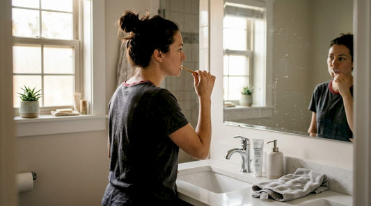 Woman brushing teeth in bright home bathroom