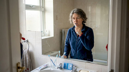 Woman brushing teeth at home sink