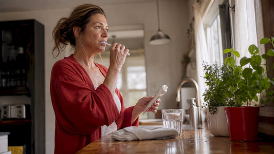 Woman brushing sensitive teeth in bathroom