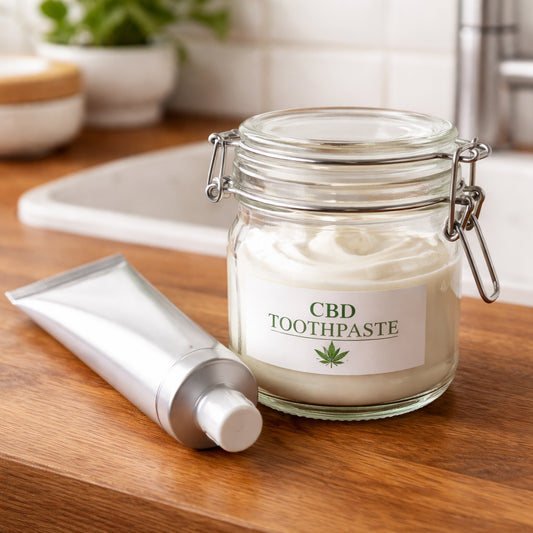 A realistic close-up of a sleek, empty toothpaste tube next to a reusable glass jar with a tight lid, on a wooden countertop. Alt: storing CBD toothpaste in a glass container