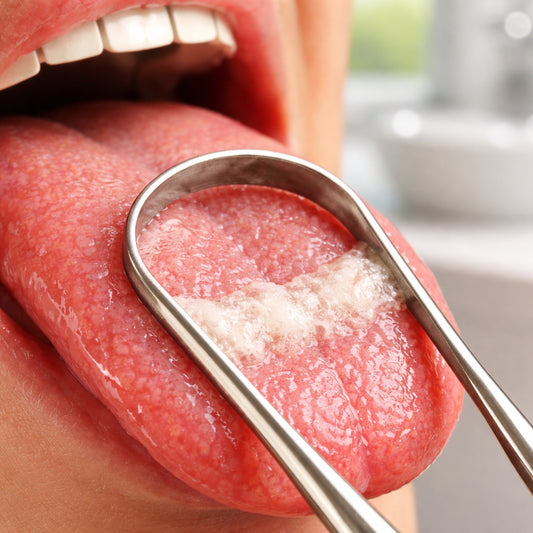 A photorealistic close‑up of a stainless‑steel tongue scraper gently gliding across a moist tongue, highlighting the removed white bio‑film, with soft natural lighting and a subtle background of a modern bathroom sink.